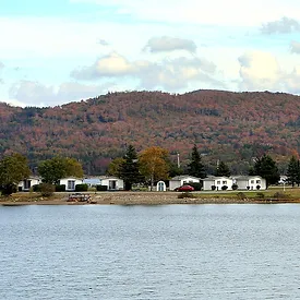 A serene lake bordered by houses, with majestic mountains rising in the background, creating a picturesque landscape.