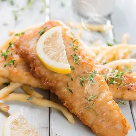 A fish and fries under it and a lemon for garnish